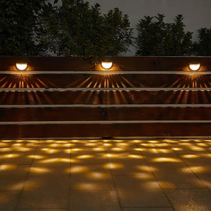 Éclairage mural solaire dans un jardin de nuit, diffusant une lumière douce et décorative sur un mur en pierre naturelle.